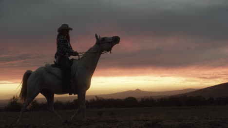 a-young-woman-riding-a-horse-on-a-ranch-at-sunset