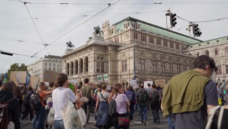 Vista-De-Los-Manifestantes-Caminando-Frente-A-La-Fachada-De-La-ópera-Durante-Los-Viernes-Para-Futuras-Protestas-Contra-El-Cambio-Climático-En-Viena,-Austria