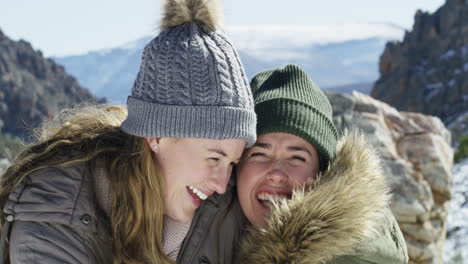 Dos-Mujeres-Jóvenes-Divirtiéndose-En-Una-Montaña-Nevada