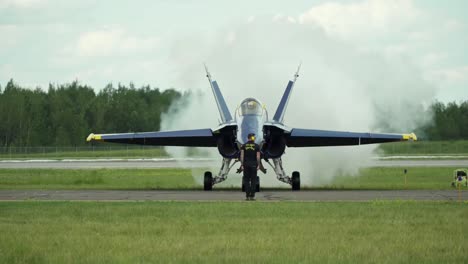 As-a-Blue-Angel-F-18-Hornet-aircraft-starts-it's-engine,-a-plume-of-smoke-is-suddenly-expelled-into-the-air-at-the-rear