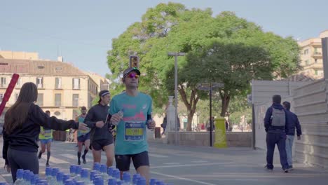 Slow-motion-shot-of-the-runner-taking-water-bottle-from-marathon-water-dispensing-point,-Malaga,-city-center