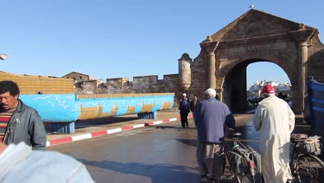 Movimiento-De-Steadicam-Moviéndose-A-Través-Del-Puerto-Pesquero-Hasta-La-Antigua-Puerta-De-Essaouira,-Marruecos