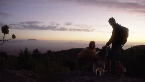 a-couple-hiking-with-their-dog-at-sunset