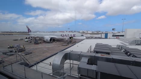 Airplane-Loading-Cargo-At-Sydney-Airport---People-Working-And-Lifting-Equipment-Transfer-Items-Under-The-Bright-Cloudy-Sky---Wide-Shot