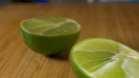 CLOSE-UP,-Lime-Cut-In-Half-With-Serrated-Knife-On-Wooden-Board