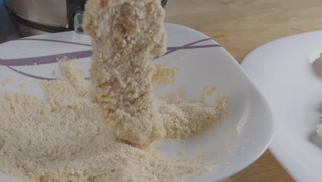 Slow-Motion-Slider-Shot-of-Breading-Chicken-Breast-Pieces-With-a-Bowl-of-Breadcrumbs-in-the-Kitchen