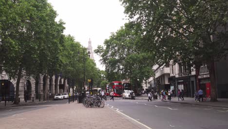 Daylife-in-London,-street-with-few-cars,-red-double-decker-buses-and-few-people,-good-weather