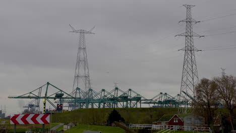 Power-lines-towering-over-the-industrial-site-of-Antwerp-Harbor,-Belgium-on-a-cloudy-day---Wide-shot