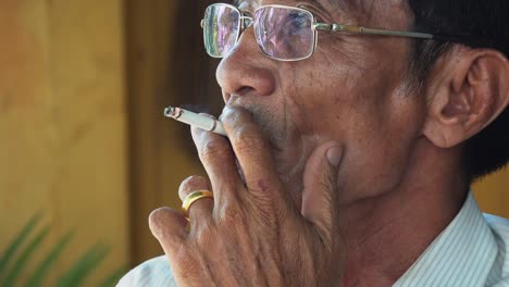 Close-Up-Shot-of-an-Elderly-Asian-Man-Enjoying-a-Cigarette