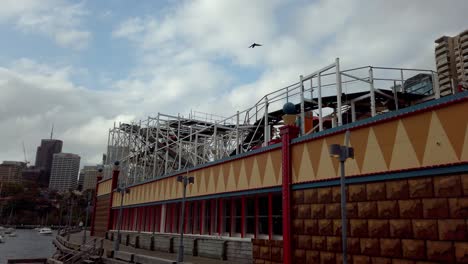 Luna-Amusement-Park-rollercoaster-ride-seen-from-the-outside-back-boardwalk-area,-Closing-in-reveal-shot