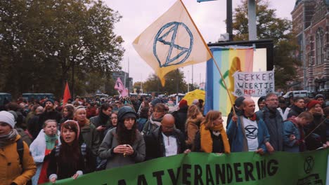 Pan-of-Extinction-Rebellion-Protesting-in-the-Street-in-Amsterdam-With-People-Chanting-and-Waving-Flags