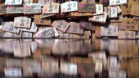 Japanese-Wishing-Cards-Reflecting-On-The-Water-At-The-Shrine-In-Japan---Closeup-Shot