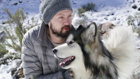 a-young-man-having-fun-with-his-dog-on-a-snowy