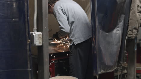 Tradesman-grinding-metal-parts-with-sparks-flying-in-a-trade-school-welding-booth