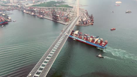 Cosco-mega-Container-Ship-crossing-Hong-Kong-Stonecutters-bridge,-heading-to-port