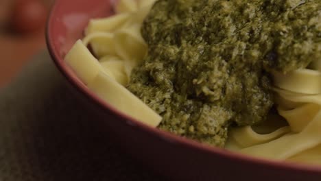 Serving-of-green-pesto-and-tagliatelle-pasta-rotating-macro-shot