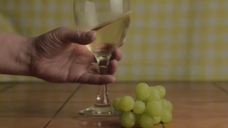 Hand-Mit-Einem-Glas-Weißwein-Und-Trauben-Aus-Nächster-Nähe