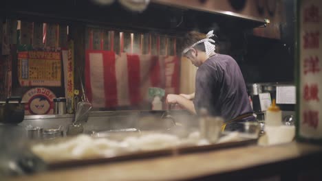 Chef-Cooking-A-Delicious-Food-For-Customers-In-A-Traditional-Japanese-Izakaya-At-Night-In-Kyoto,-Japan