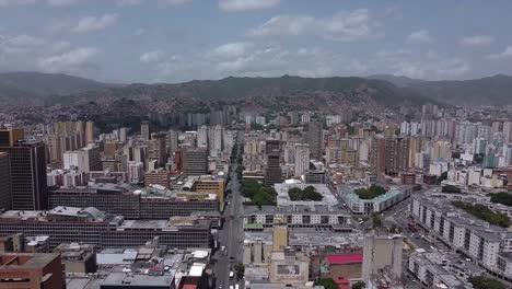 Daytime-flight-over-Baralt-Avenue,-downtown-Caracas,-showing-the-cityscape-surrounded-by-a-mountain-range