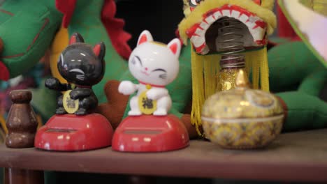 Asian-Plastic-Kitten-Decorations-And-Dragon-Waving,-TILT-UP
