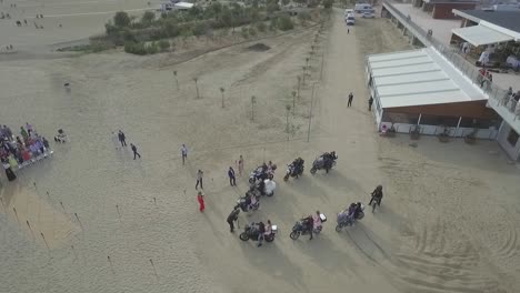 Bride-arrives-to-her-wedding-on-the-back-of-a-motorcycle-in-the-beach-surrounded-by-rider-friends