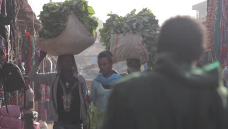 Woman-and-Two-Men-Carrying-Produce-Through-African-Marketplace