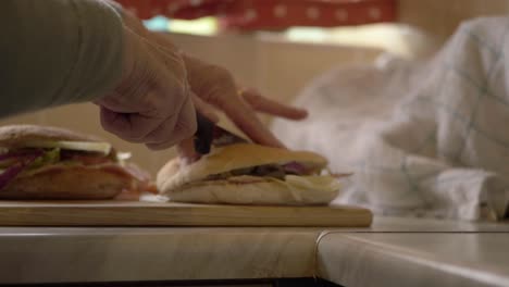 Woman's-hands-cutting-prepared-sandwiches-in-kitchen-medium-shot