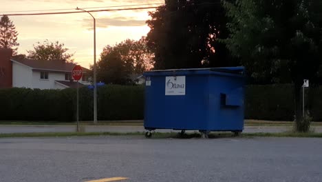 Blue-City-of-Ottawa-dumpster-at-edge-of-parking-lot-on-summer-evening-in-Ottawa-Ontario-Canada