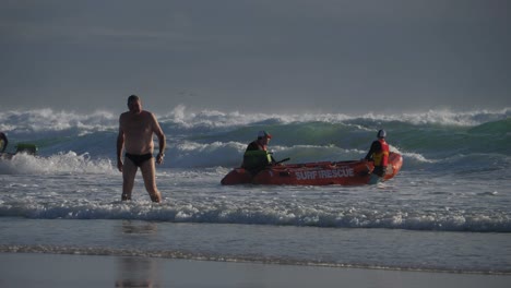 Man-Leaving-The-Ocean-After-Enjoying-Swimming-On-Summer---Surf-Lifesaving-Team-On-Duty-On-A-Rescue-Boat---Currumbin-Beach-In-Gold-Coast,-QLD,-Australia