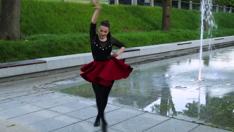 Female-does-a-dance-routine-outside-next-to-a-fountain
