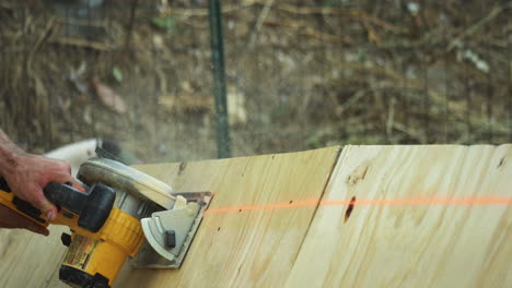 Man-uses-a-power-saw-to-quickly-cut-off-the-edge-of-a-large-piece-of-plywood