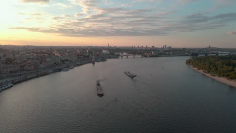 Aerial-shot-of-ships-sailing-on-the-Dnipro-river-near-Kiev-with-the-sunset-behind