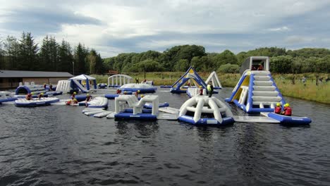 Colorful-Inflatable-Obstacles-On-The-Water-In-Splash-Valley-Aqua-Park-In-Rathdrum,-Wicklow,-Ireland-With-People-Having-Fun---wide-shot
