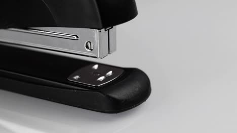Close-up-shot-of-a-person-stapling-a-piece-of-paper-with-a-black-stapler