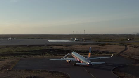 Circle-pan-aerial-around-Boeing-757-during-beautiful-sunlight-on-Iceland-tarmac