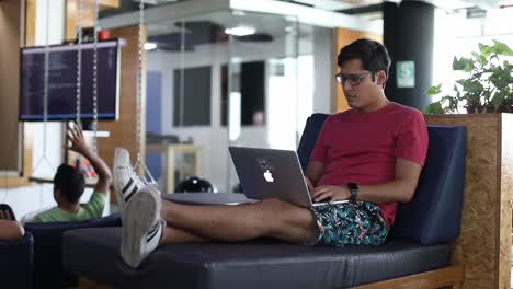 Millennial-at-a-trendy-startup-office-sits-on-modern-furniture-working-on-a-laptop