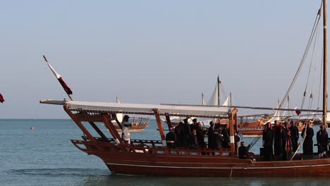 A-view-of-traditional-wooden-boat-known-as-Dhow,-carrying-a-group-of-local-people-singing-and-dancing-at-Katara-Village,-Doha,-Qatar-on-the-occasion-of-Dhow-Festival