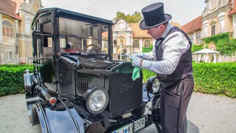 Man-with-formal-vest-and-top-hat-wipes-Ford-Model-T-car's-hood-ornament
