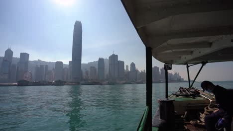Hong-Kong,-China,-Crossing-Victoria-Harbour-Water-on-Star-Ferry-Boat,-Cityscape-in-Background-on-Sunny-Day-During-Covid-19-Virus-Pandemic