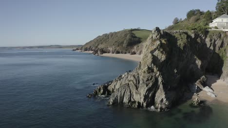 A-forward-flying-shot-past-a-cliff,-over-a-calm-sea-revealing-another-sheltered-cove