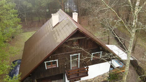 Aerial-slow-take-off-shot-over-old-traditional-Polish-brown-wooden-house-in-the-forest-Bartoszylas