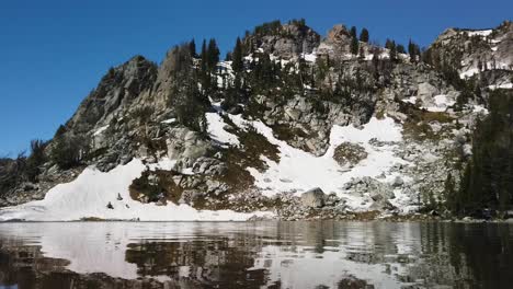 Superficie-Tranquila-Y-Reflectante-Del-Lago-Sorpresa-Y-Las-Montañas-Más-Allá-En-El-Parque-Nacional-Grand-Teton-En-Wyoming-En-Un-Día-Soleado-De-Verano