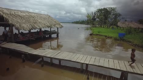 Vista-De-Drones-De-Un-Grupo-De-Niños-Indígenas-Warao-Corriendo-En-Una-Casa-Flotante-En-El-Río-Orinoco