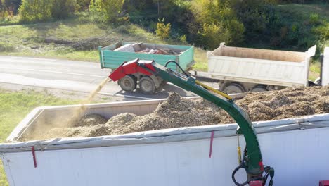 Wood-Chipper-Loading-Up-Lorry-Trailer-Beside-Road-In-Slovenia-With-Traffic-Going-Past