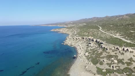 Slow-aerial-push-in-across-land-and-beautiful-clear-turquoise-sea-on-the-coast-of-Akamas-Peninsula-in-Cyprus-Paphos