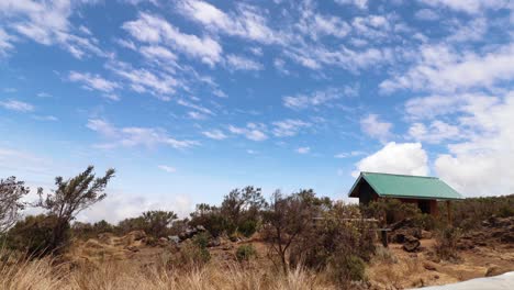 Time-lapse-shot-of-a-cabin,-plants-and-nature,-Clouds-moving-in-a-blue-sky,-on-mount-Kilimanjaro,-on-a-sunny-day,-in-Tanzania,-Africa