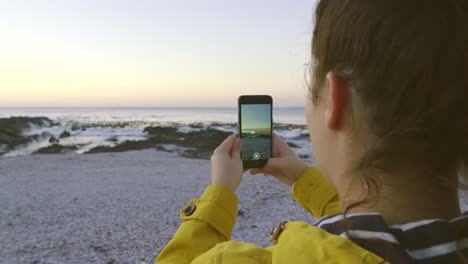 Tourist-using-a-phone-on-a-beach-to-photograph