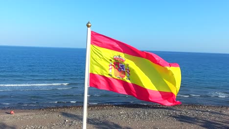 Rotierende-Aufnahme-Der-Spanischen-Nationalflagge-Am-Strand