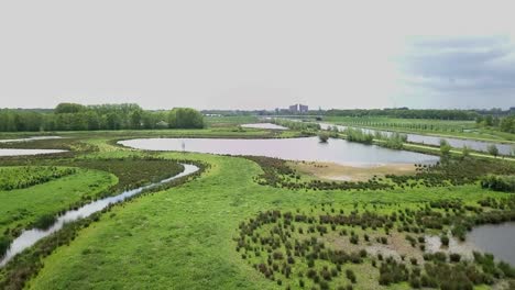 Footage-of-flying-up-over-the-river-and-green-savanna-near-the-canal-in-Holland
