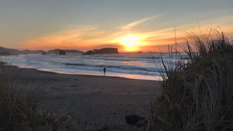 Sunset-at-Bandon-Beach,-one-person-is-fishing-from-the-beach